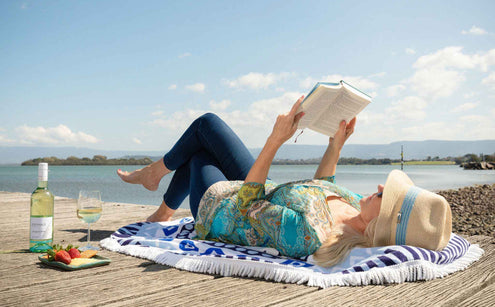 Women on a beach dock with white wine and reading a book