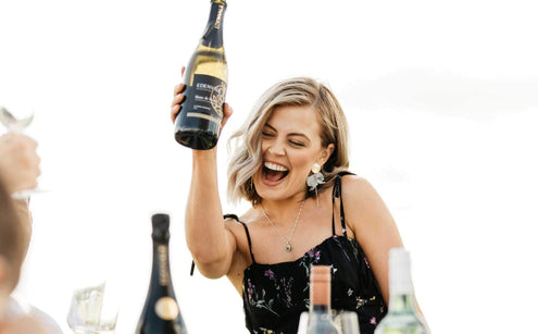 Women holding a bottle of wine cheering