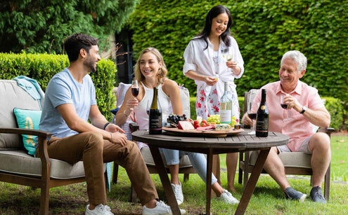 Four adults seated at an outdoor party table drinking non-alcoholic wine and socialising