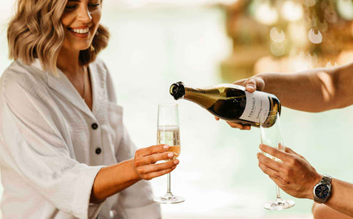 Women getting a glass of white wine poured for her