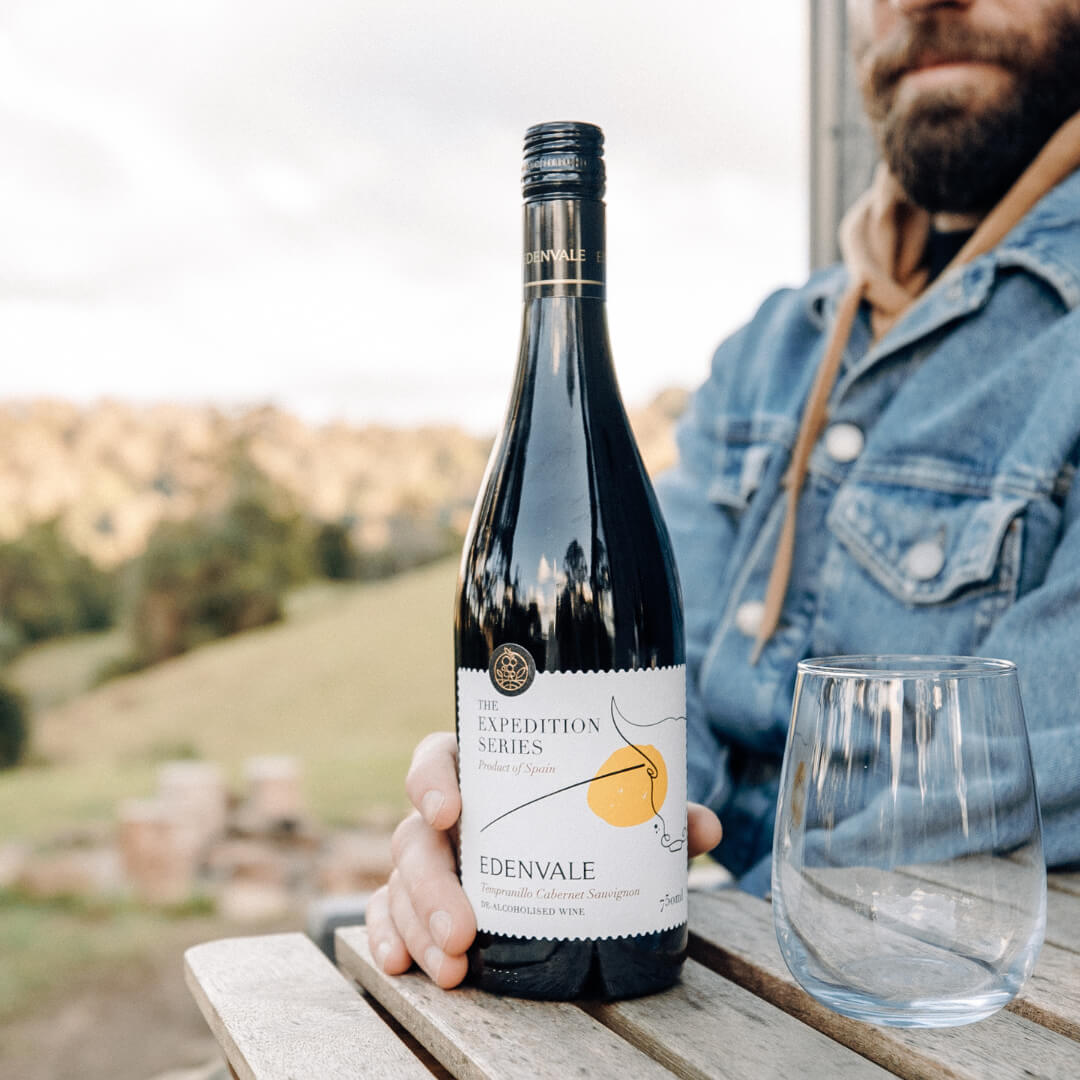 Man sitting in the countryside about to open a bottle of Edenvale red wine