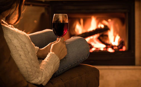 Someone sitting at the fire with wine