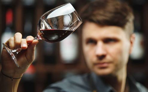 Man holding a wine glass full of wine inspecting it