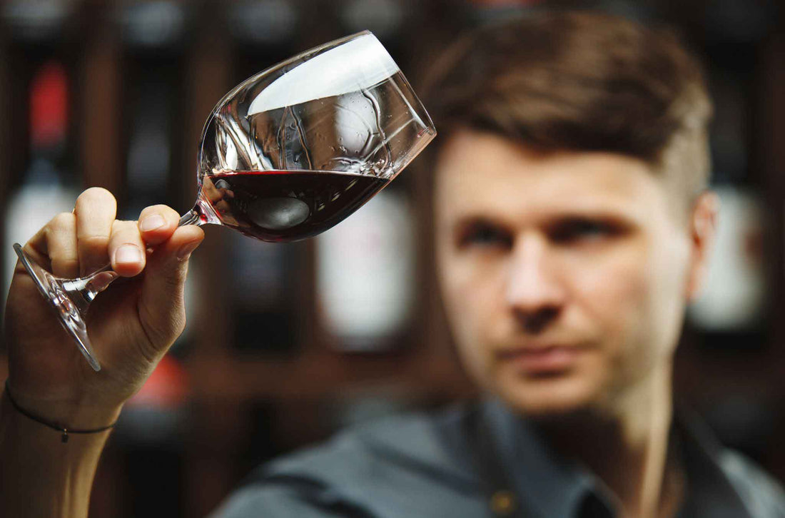 Man holding a wine glass full of wine inspecting it