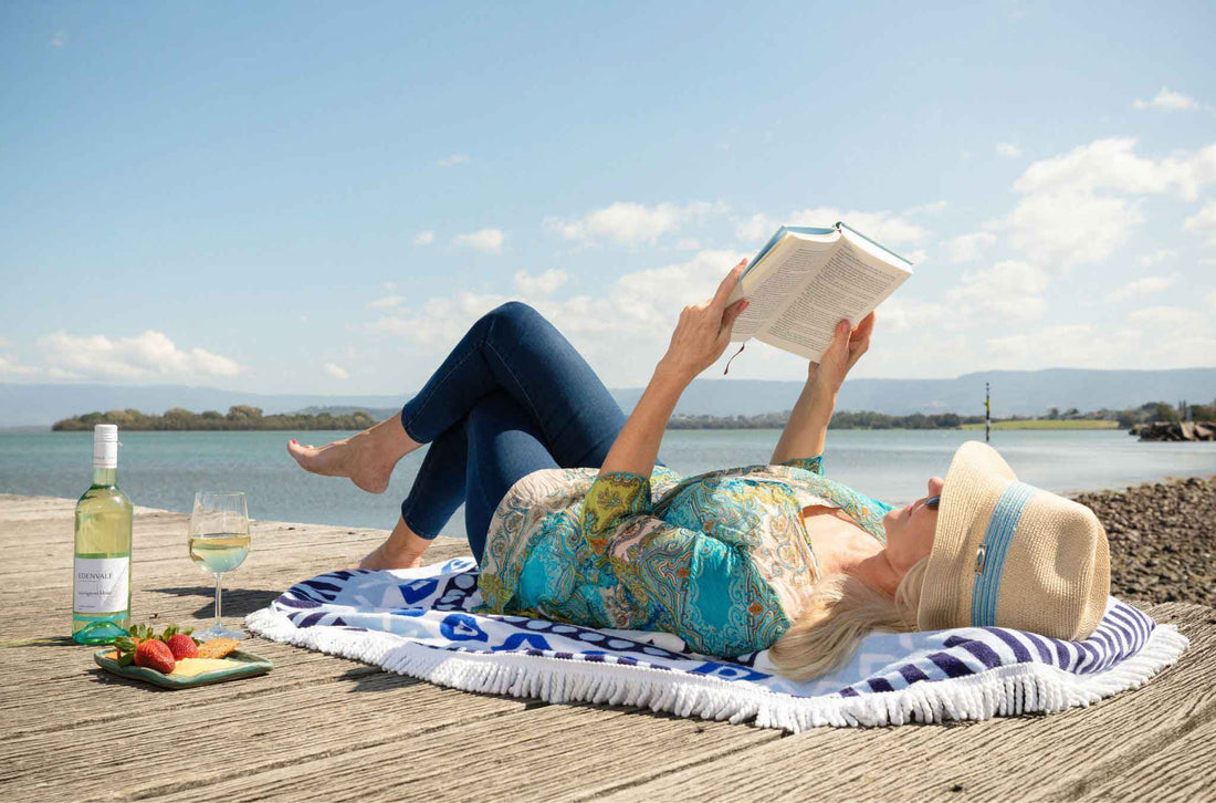 Women on a beach dock with white wine and reading a book