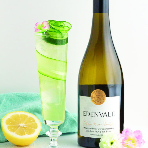  Cucumber Elderflower Spritz mocktail with cucumber garnish, cut lemon and blossoms beside a bottle of Edenvale Semillon Sauvignon Blanc