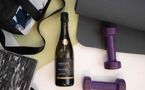 Bottle of Edenvale Blanc de Blanc lying alongside a gym bag and purple dumbbell