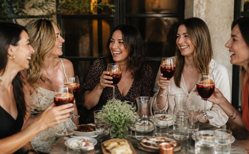 Friends toasting with non-alcoholic Red Sangria mocktail at a lunch