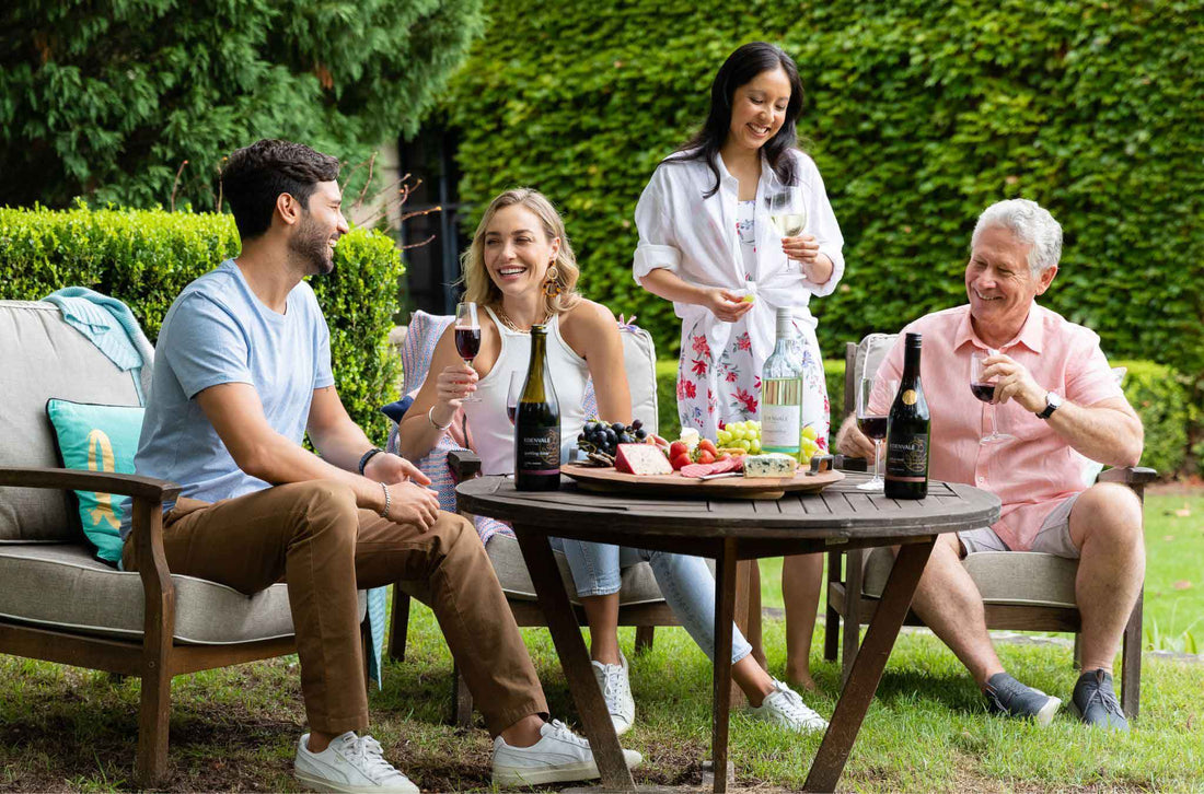 Four adults seated at an outdoor party table drinking non-alcoholic wine and socialising