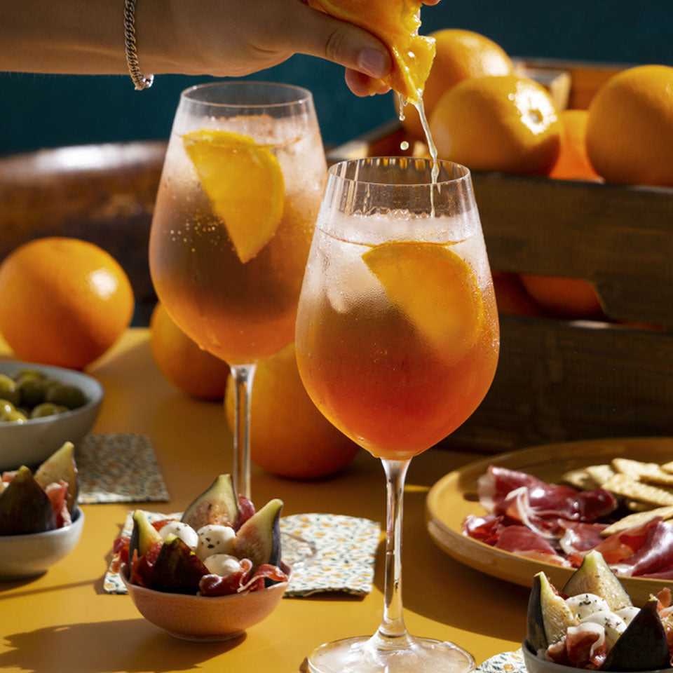 Close-up shot of hand squeezing juice from orange. Black background.