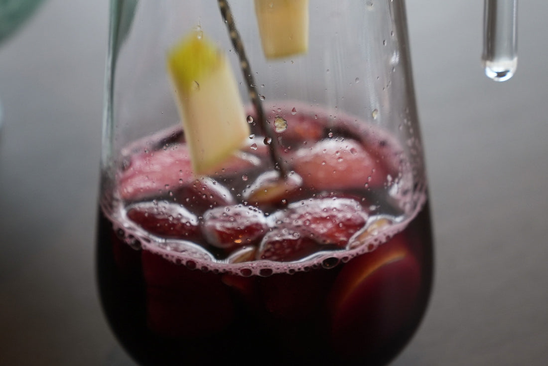Close-up of non-alcoholic Red Sangria mocktail with apple slices and ice cubes being added to the glass