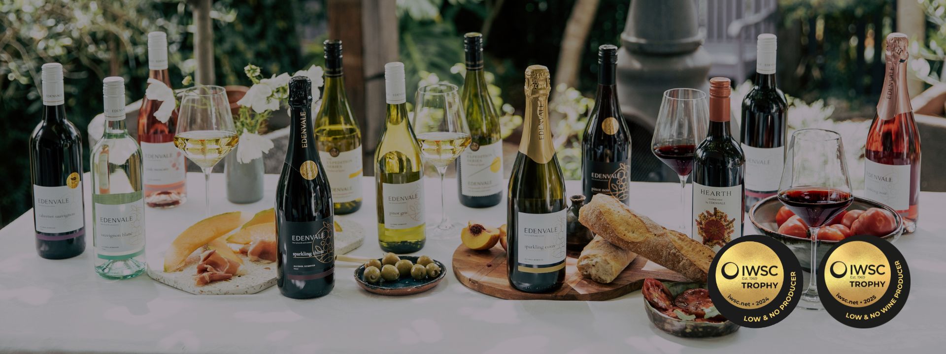 Table with various wine bottles and food items, featuring IWSC logos.